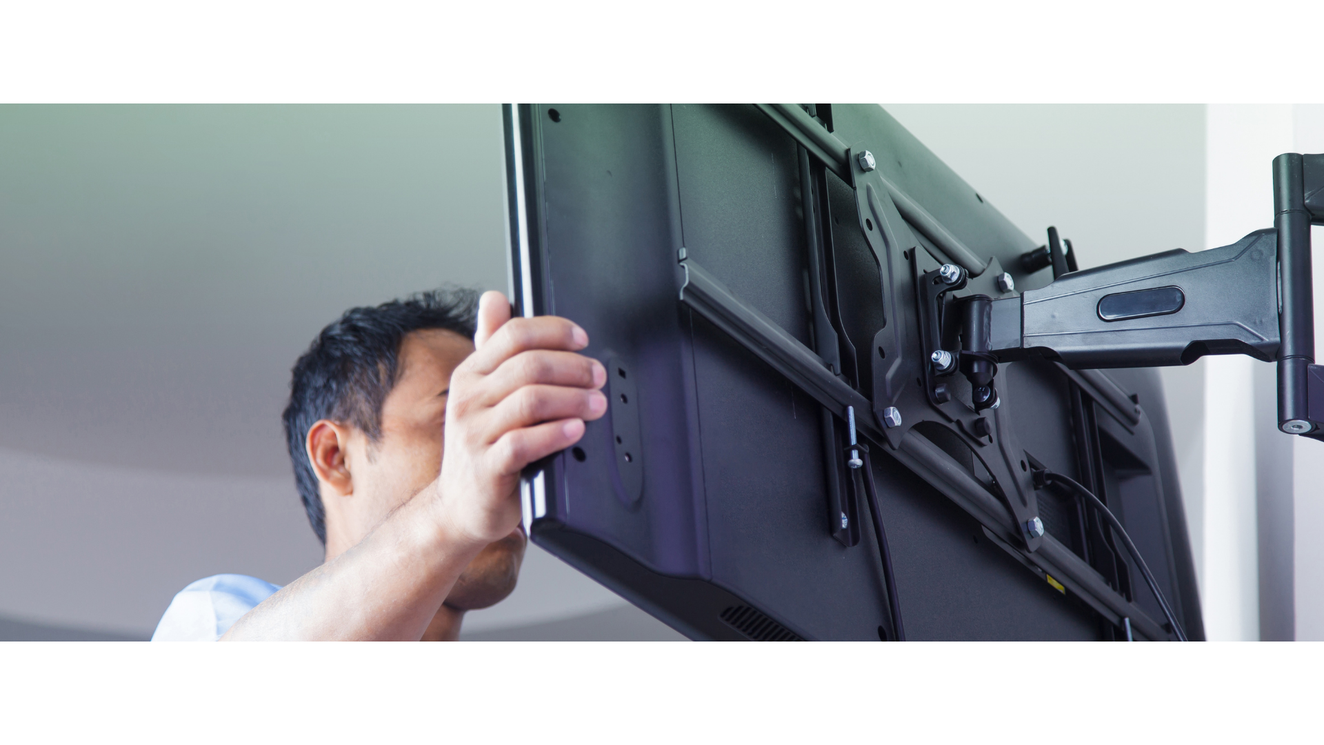 Mężczyzna zawieszający monitor na ścianie